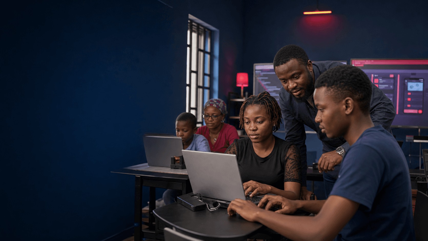 African learners collaborating with a technology instructor during a practical workshop
